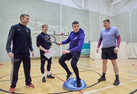 students on a balance board in the gym
