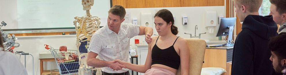 Lecturer demonstrating shoulder movement with a student