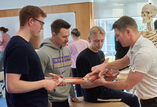 students looking at an anatomical arm