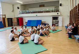 A group of students sitting on gym mats