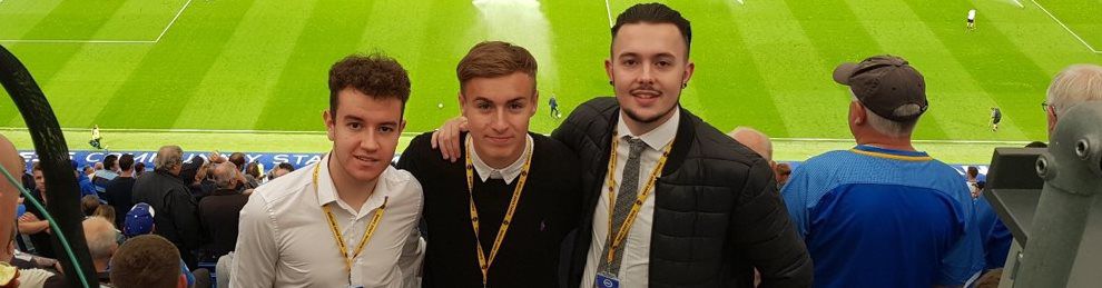 Three Sport Journalism Apprentices in front of a football pitch