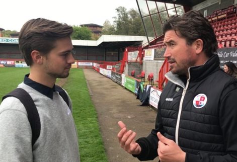 A student on a football pitch doing an interview