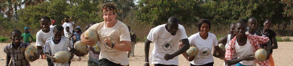 People running towards the camera holding rugby balls