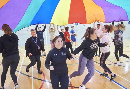Sports students playing with coloured parachute