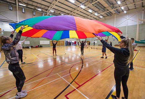 Sports students teaching with coloured parachute