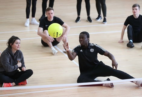 Students playing sit down volleyball