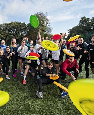 People throwing frisbees at the camera