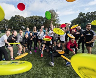 Students throwing frisbees at the camera