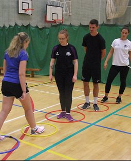 Four students standing in rings in an exercise hall