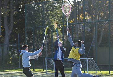 Three students playing lacrosse