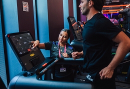 Gym instructor helping person on treadmill
