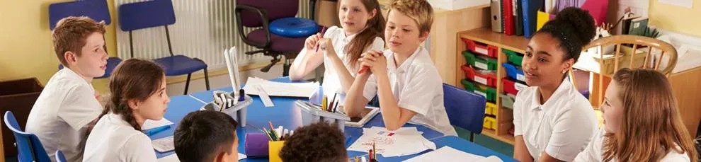 Primary pupils working together in a group around a table in a classroom