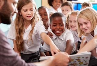 Primary school children taking part in shared reading with a teacher.