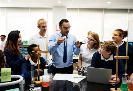 Secondary teacher leading a practical science lesson with pupils using laboratory equipment