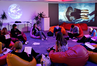 A group of about ten students sitting on bean bags in a circle