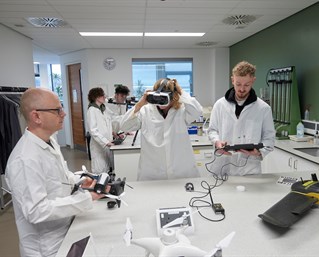 People in a lab experimenting with dones and VR headsets