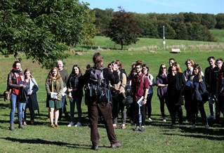 A group of students facing their teacher in a field