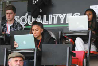 People writing on laptops at an outdoor sporting event