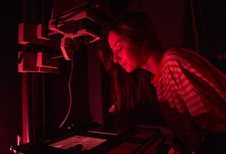 A student processing a photo in a dark room