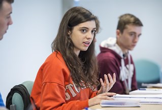 A student gesticulating as they ask a question