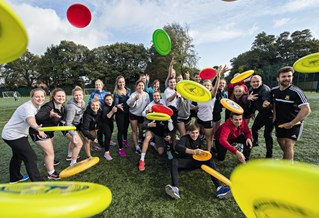 A group of students throwing frisbees at the camera