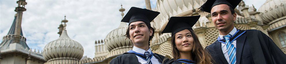 Three graduates in mortar boards and gowns in front of the Royal Pavilion