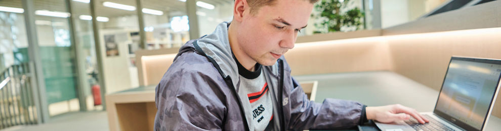 Student reading and working on a laptop