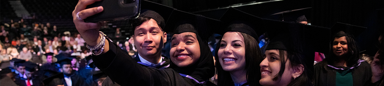 Four graduates posing for a selfie at graduation