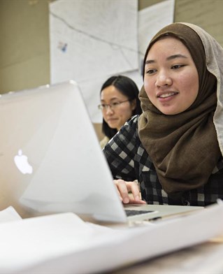 Student in hijab working on laptop