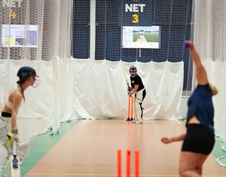 Three female cricketers in indoor facility