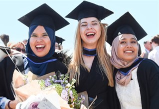 Three graduates with blue sky in the background