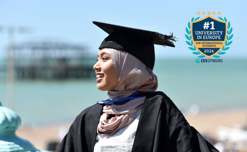 Student in a graduation gown and mortarboard on Brighton seafront