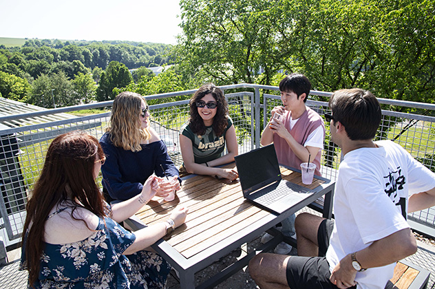 Five students around a table in the sunshine