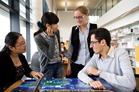 Group of four international students looking at a map in the library