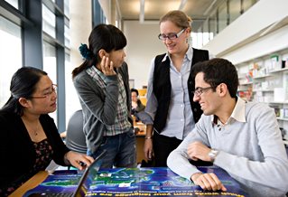 Students chatting over a desk with a large map on it