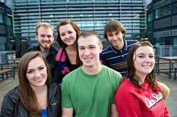 A group of students smiling in front of a university building