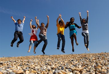 internationl students jumping on the beach