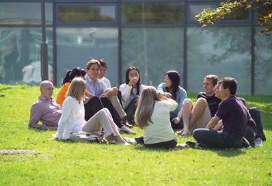 A group of students sitting on the grass in the sunshine