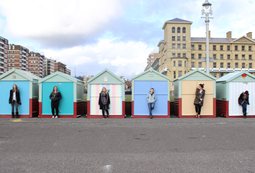 Image of beach huts at Hove with a student standing in front of each one