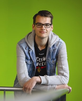 Student Andrew Baumann posing in front of a green screen