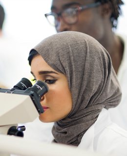 International student looking down a microscope