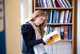 Student looking through a book in the library