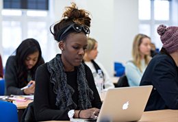 Student writing on a laptop in a lecture