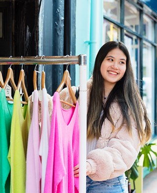 Student in Brighton lanes by a rail of clothing
