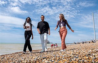 Three students walking along Brighton beach