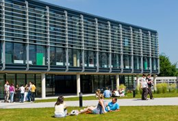 Students sitting on the grass outside Checkland building at Falmer campus