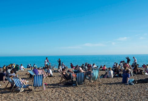 Sunny beach with people in deck chairs