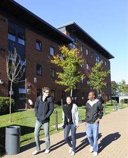 Three students with accommodation in the background