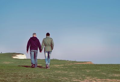 Couple walking on grass cliffs Photo by Stanley Dai on Unsplash