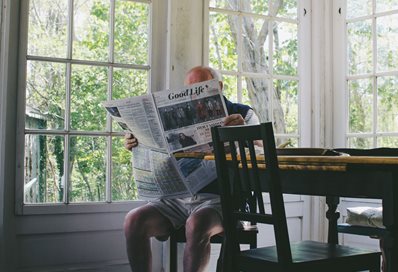 Older man reading newspaper, photo by Sam Wheeler on Unsplash